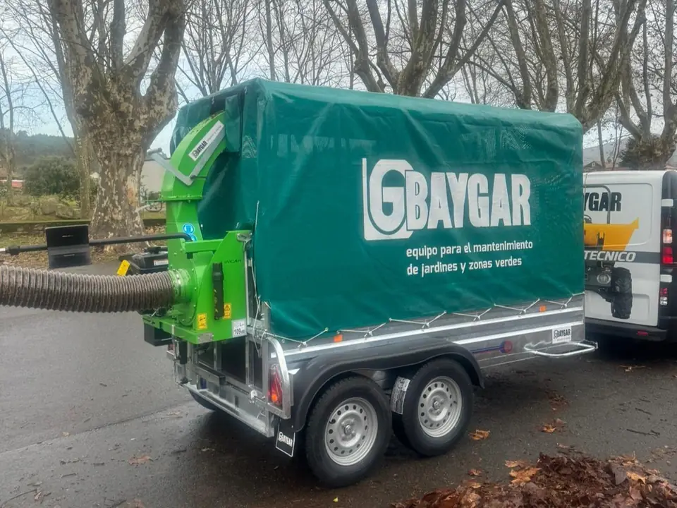 Remolque de dos ejes con lona verde de Baygar y la aspiradora de hojas enganchada