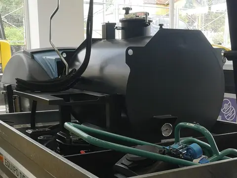 Cisterna negra de la regadora de emulsión, con su manguera