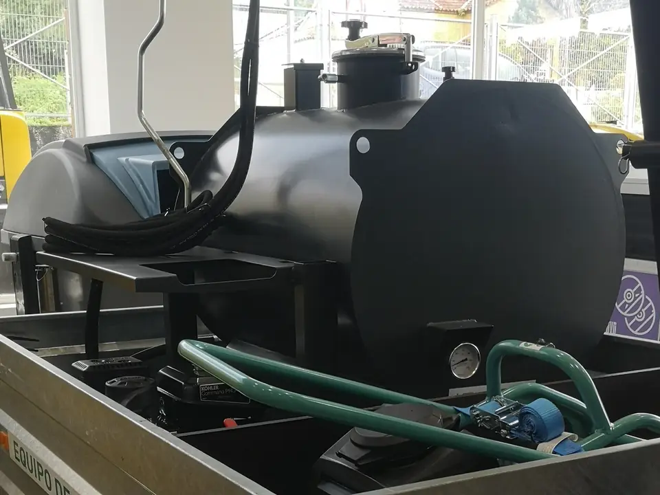 Cisterna negra de la regadora de emulsión, con su manguera
